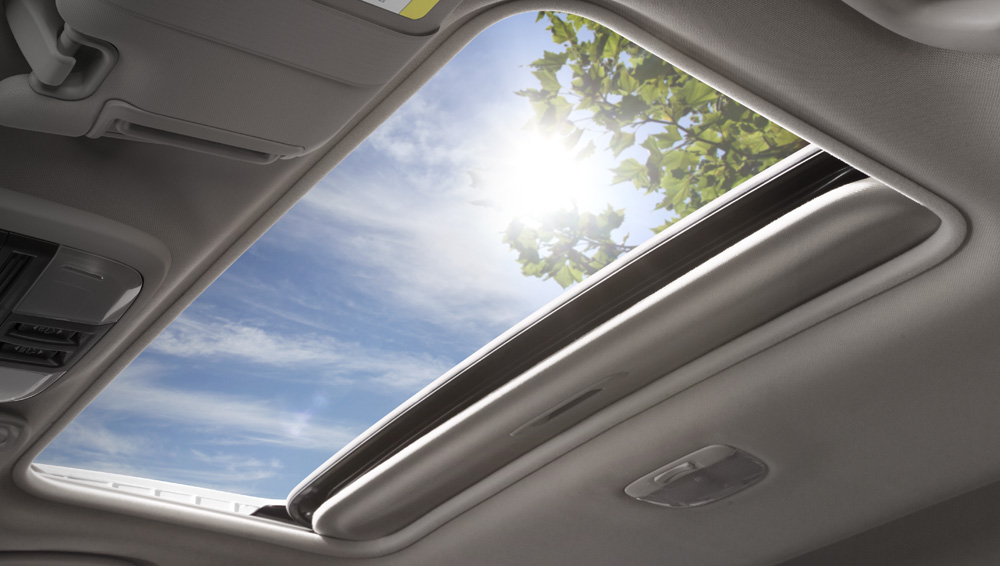 2027 Subaru Crosstrek power moonroof open to the sky and surrounding trees.